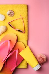 Flat lay composition with sunscreen and beach accessories on pink background