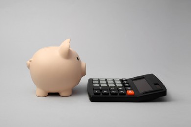 Calculator and piggy bank on grey background