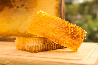 Photo of Fresh delicious honeycombs on wooden table outdoors