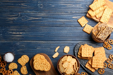 Photo of Many delicious crackers on blue wooden table, flat lay. Space for text