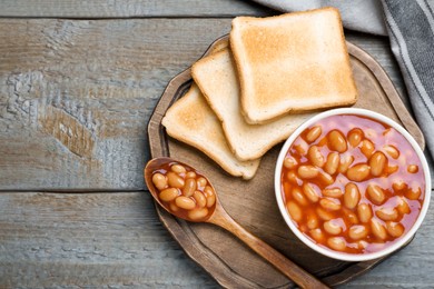 Photo of Toasts and delicious canned beans on wooden table, top view. Space for text
