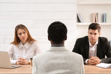 Coworkers conducting job interview with African American man in office, back view. Racism concept