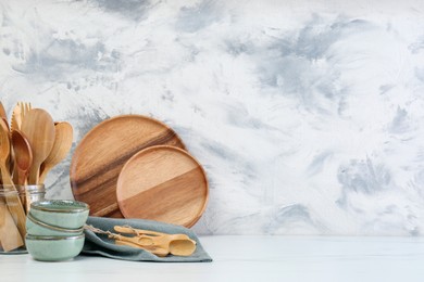 Different dishware and utensils on white marble table against textured wall. Space for text