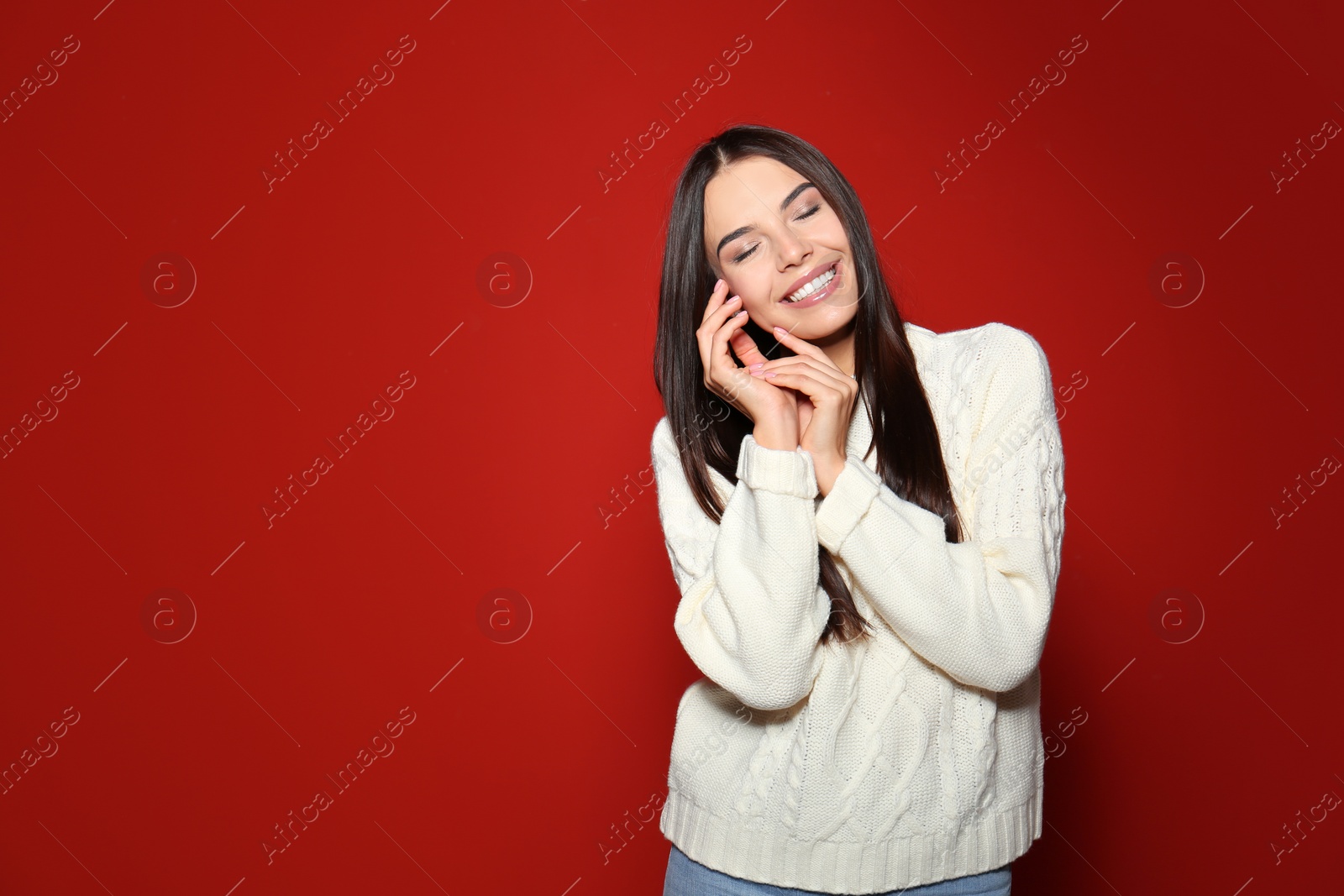 Image of Pretty woman wearing warm sweater on red background 