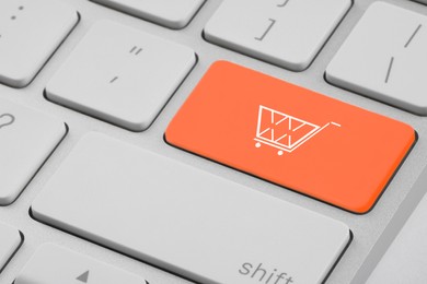 Image of Online store. Orange button with shopping cart on computer keyboard, closeup