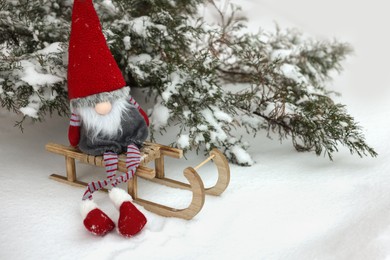 Wooden sleigh with Christmas gnome on snow outdoors