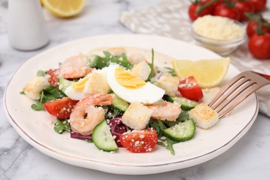 Photo of Delicious Caesar salad with shrimps on white marble table, closeup