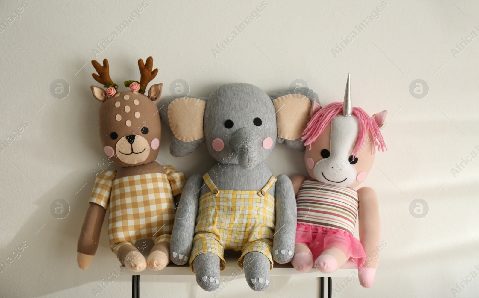 Photo of Shelf with cute toys on light wall. Baby room interior element