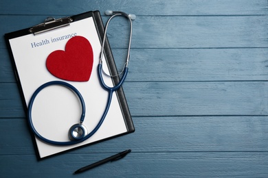 Photo of Flat lay composition with health insurance form and stethoscope on blue wooden surface, space for text