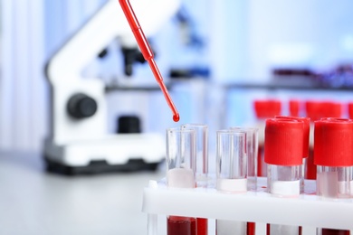 Pipetting blood into test tube for analysis on table in laboratory, closeup