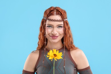 Photo of Beautiful young hippie woman with sunflower on light blue background