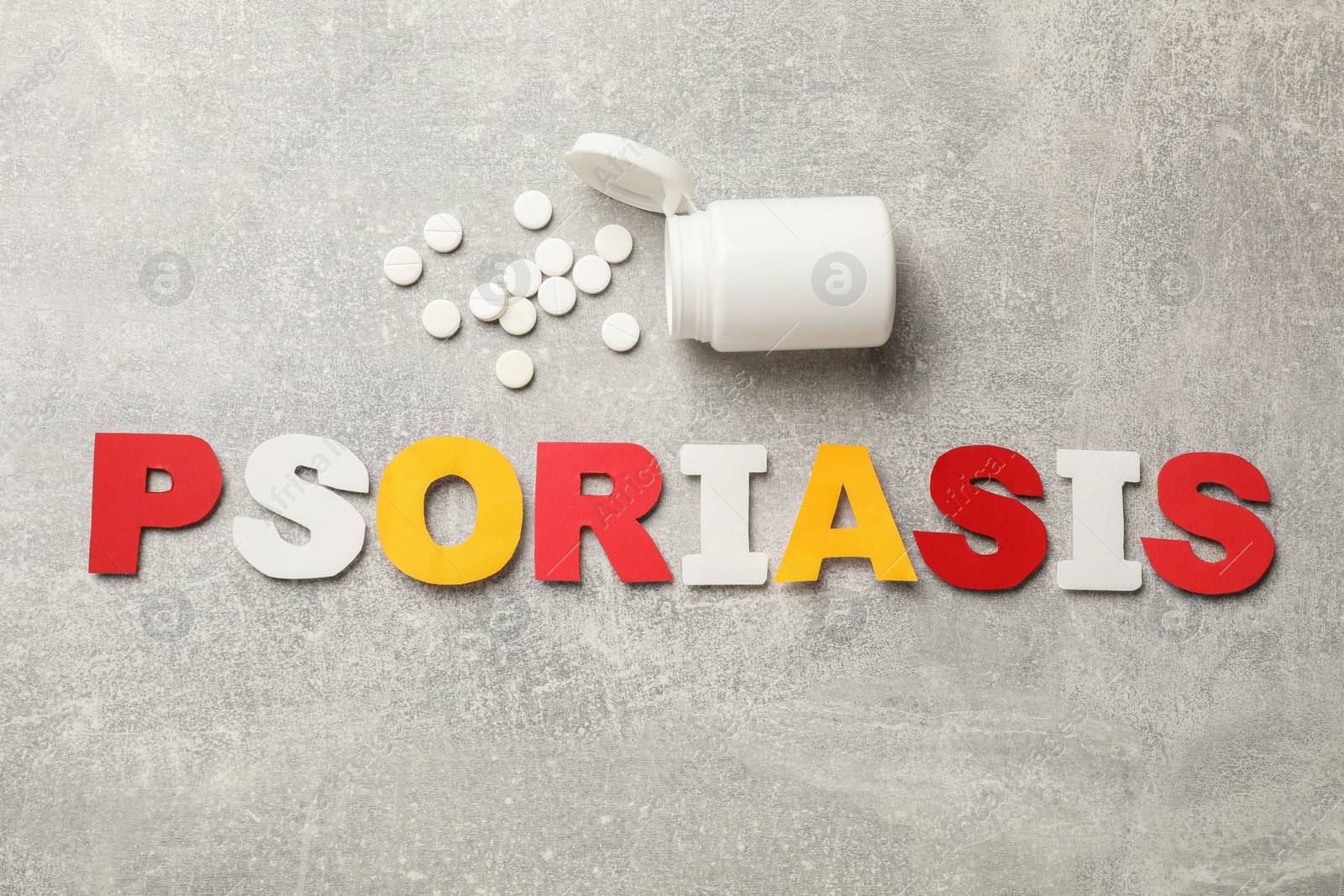 Photo of Word Psoriasis made of paper letters and pills on light gray textured table, flat lay