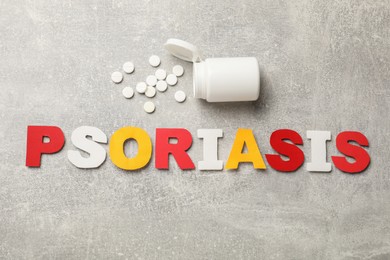 Word Psoriasis made of paper letters and pills on light gray textured table, flat lay