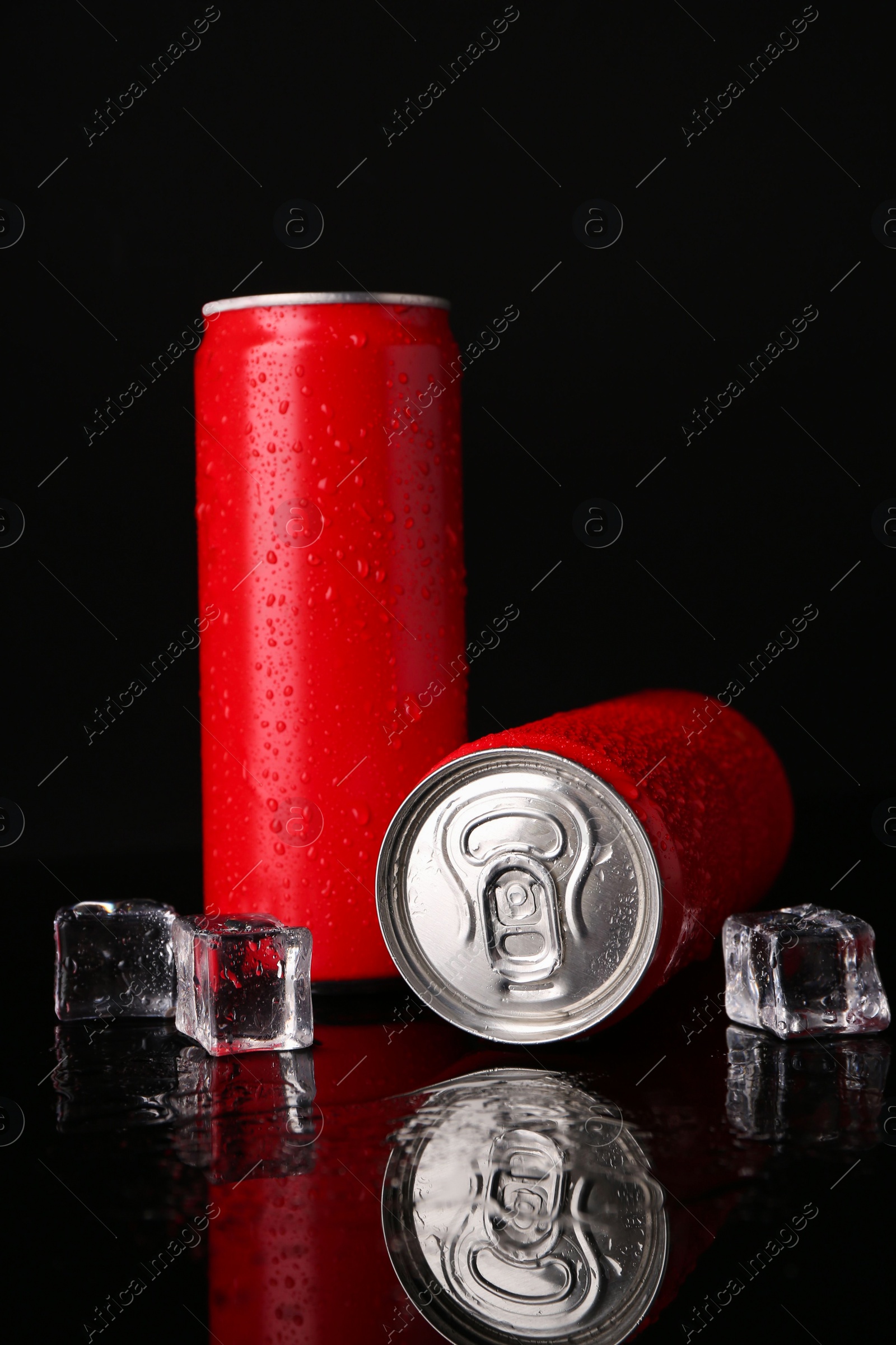 Photo of Energy drinks in wet cans and ice cubes on black background