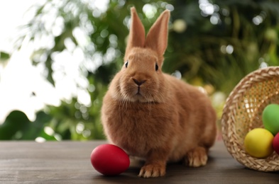Photo of Cute bunny and Easter egg on table against blurred background