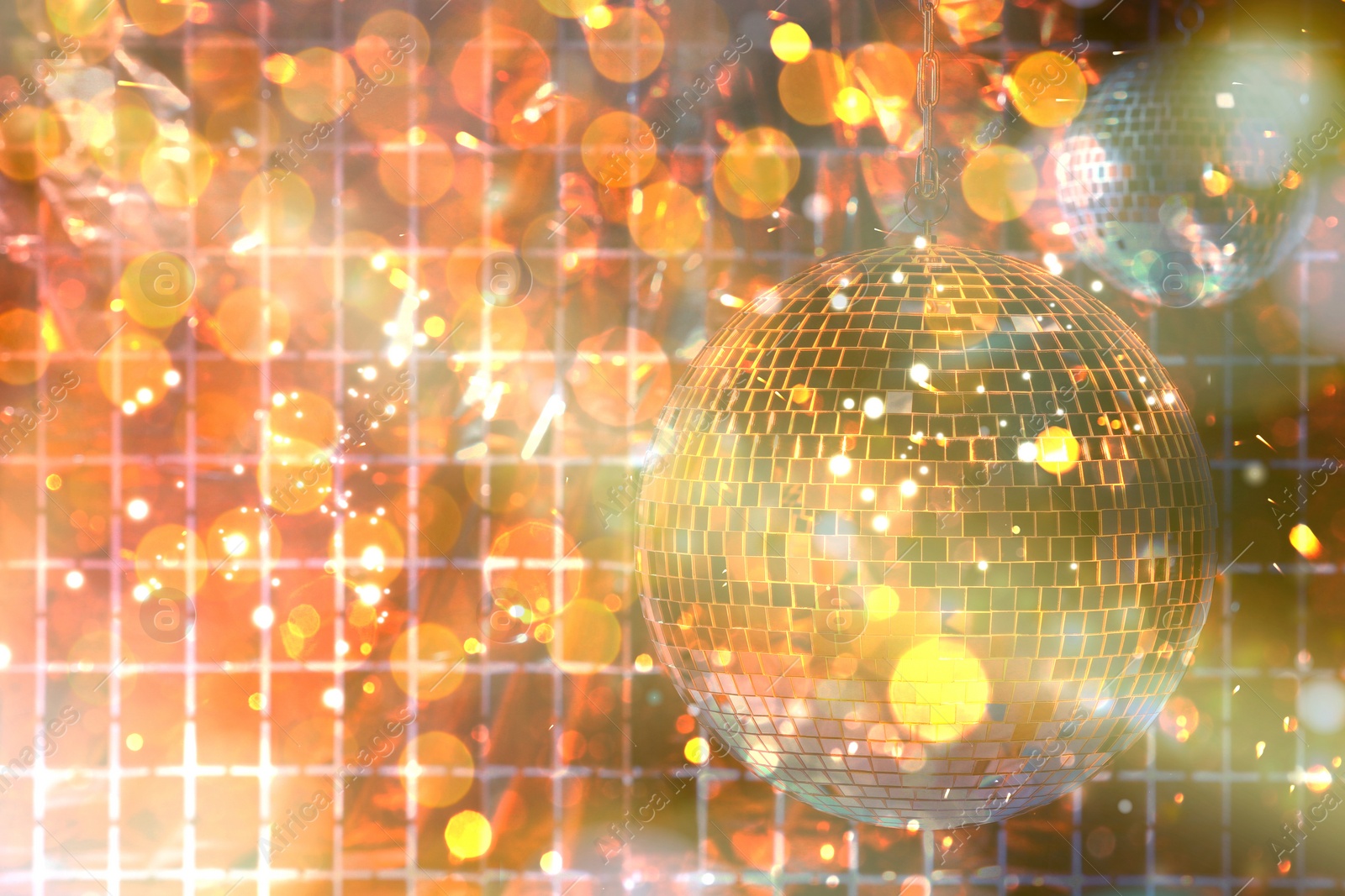 Image of Shiny disco balls against foil party curtain under golden lights, space for text. Bokeh effect
