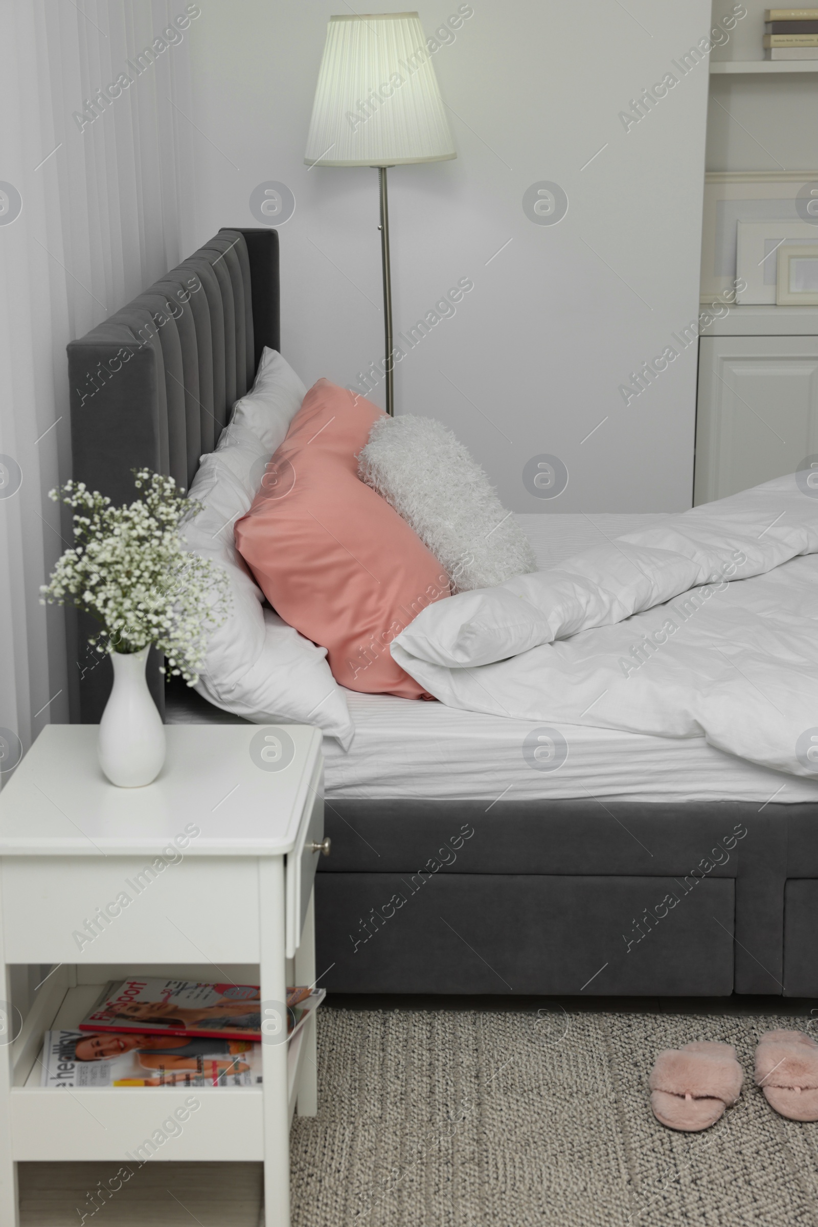 Photo of Stylish bedroom interior with comfortable bed, nightstand and lamp