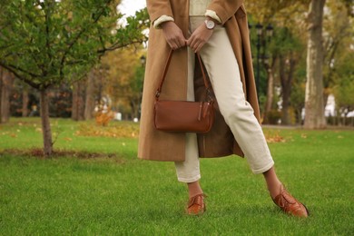 Photo of Stylish woman with trendy leather bag in autumn park, closeup