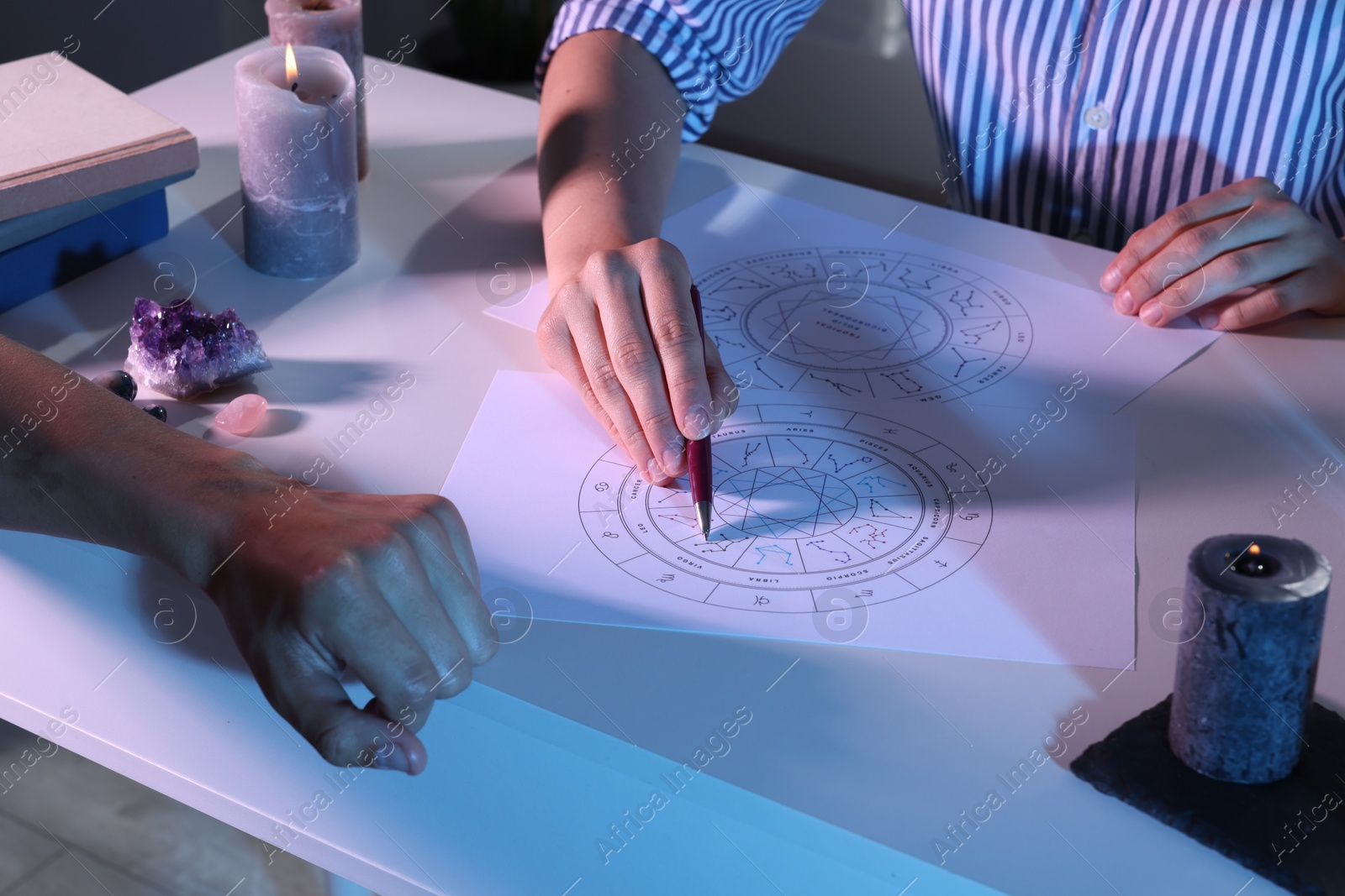 Photo of Astrologer showing natal charts to client at table, closeup