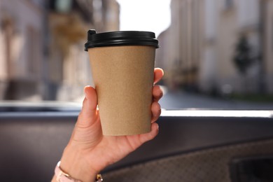 Coffee to go. Woman with paper cup of drink in car, closeup and space for text