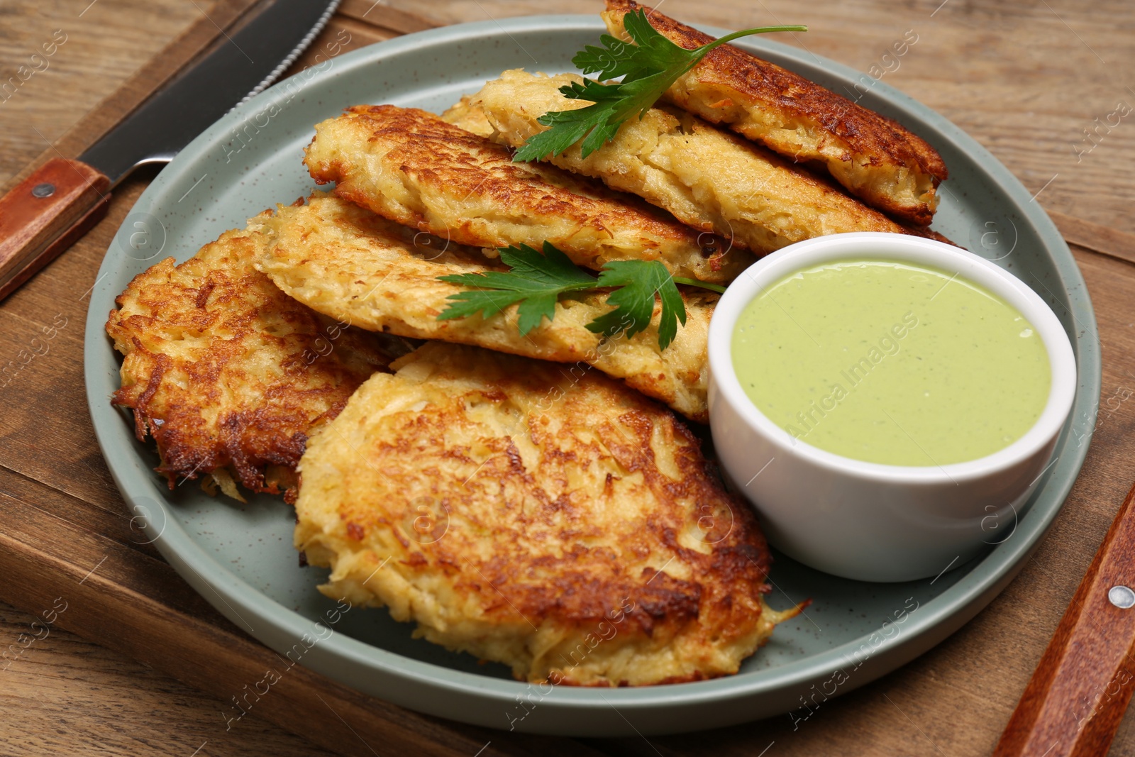 Photo of Tasty parsnip cutlets with sauce on wooden table, closeup