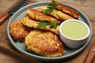 Tasty parsnip cutlets with sauce on wooden table, closeup