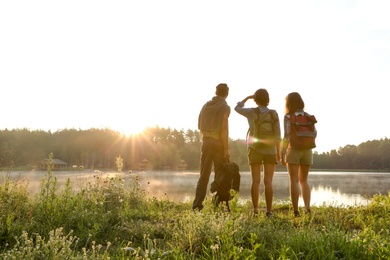 Photo of Young friends on shore of beautiful lake. Camping season