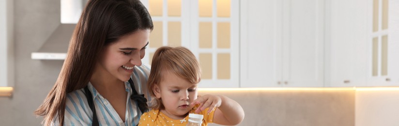 Mother and her little daughter cooking together in kitchen, space for text. Banner design