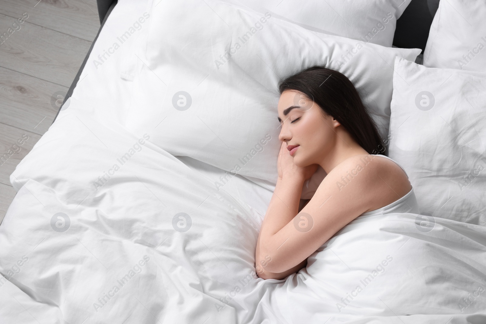 Photo of Beautiful young woman sleeping in soft bed, above view