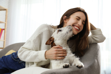 Photo of Young woman with her cute Jack Russell Terrier on sofa at home. Lovely pet