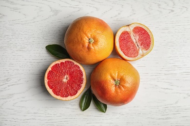 Photo of Fresh tasty grapefruits on white wooden background, top view