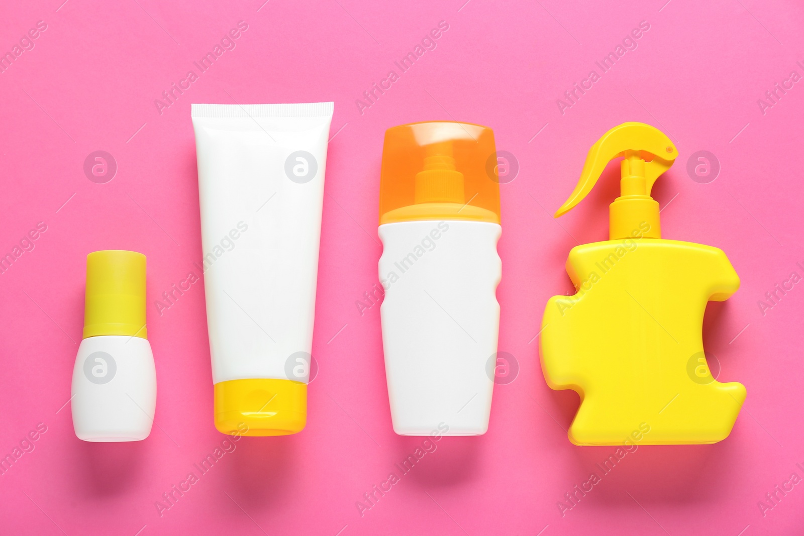 Photo of Suntan products on pink background, flat lay