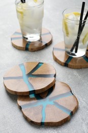 Photo of Cocktail and stylish cup wooden coasters on light grey table