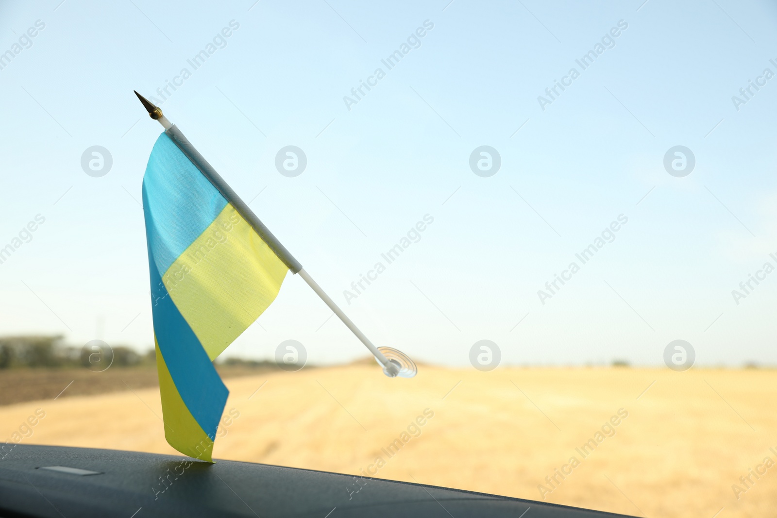 Photo of National flag of Ukraine on windshield inside car, closeup. Space for text