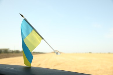 National flag of Ukraine on windshield inside car, closeup. Space for text