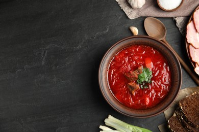 Stylish brown clay bowl with Ukrainian borsch served on black table, flat lay. Space for text