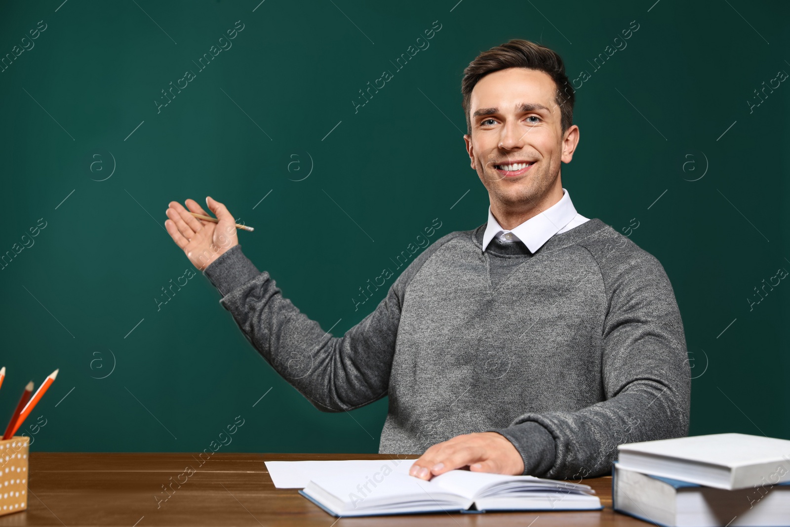 Photo of Portrait of male teacher working at table against color background