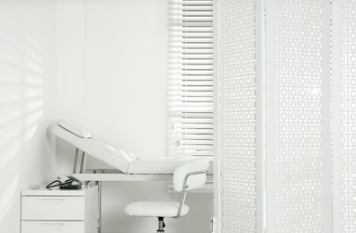 Examination room with modern couch and folding screen in clinic