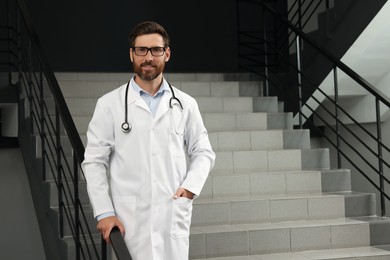 Photo of Doctor with stethoscope on stairs in hospital. Space for text