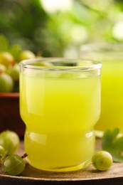 Tasty gooseberry juice and fresh berries on wooden tray, closeup