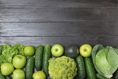 Photo of Ripe green fruits and vegetables on black wooden table, flat lay. Space for text