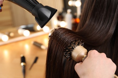 Photo of Hairdresser blow drying client's hair in salon, closeup