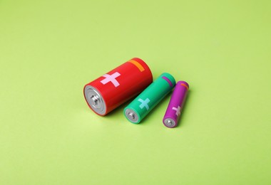 Photo of Batteries of different sizes on light green background