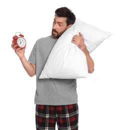 Photo of Excited overslept man with alarm clock and pillow on white background
