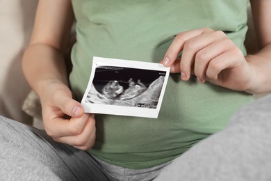 Photo of Pregnant woman with ultrasound picture of baby, closeup