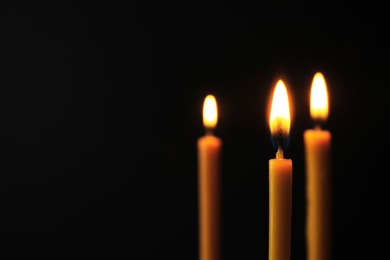 Photo of Burning candles on dark background, space for text. Symbol of sorrow
