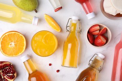 Photo of Tasty kombucha in bottles, glass and fresh fruits on white marble table, flat lay