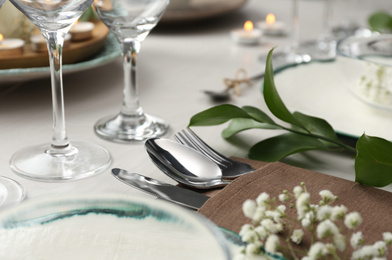 Elegant cutlery with green plants on table, closeup. Festive setting