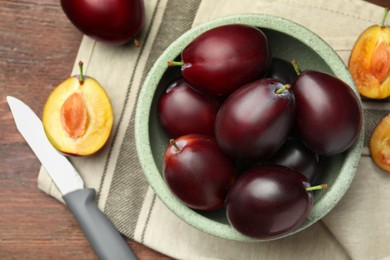 Photo of Tasty ripe plums on wooden table, flat lay