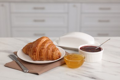 Breakfast time. Fresh croissant, jam and honey on white table